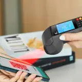 Pagamento contactless con smartphone e sistema pos. Un QR code sullo schermo del telefono viene scansionato dal terminale.