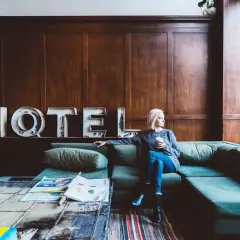 Donna seduta su un divano in un hotel, pensando a un possibile infortunio in albergo e al risarcimento danni.