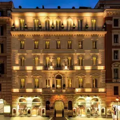 Edificio illuminato di notte, con negozi al piano terra. Si percepisce la differenza tra hotel 3 stelle e 4 stelle dall'eleganza.