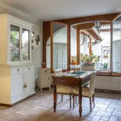 Un tavolo da pranzo con sedie, un mobile bianco e un'ampia finestra che si apre su un cortile. Il **motel significato** qui è un luogo accogliente, non solo un posto dove dormire.
