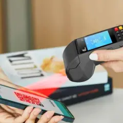 Pagamento contactless con smartphone e sistema pos. Un QR code sullo schermo del telefono viene scansionato dal terminale.
