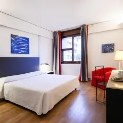 Camera accogliente con letto, poltrona rossa e vassoio colazione, perfetta per un day use rilassante.