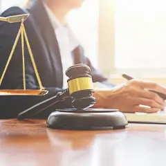 Bilancia della giustizia, martelletto e mano che scrive. Valutare le implicazioni legali per affittare su Airbnb senza partita IVA.