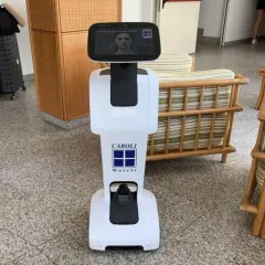 Un hotel robot bianco con logo Caroli Hotels accoglie i visitatori.
