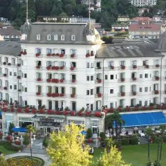 Hotel Regina Palace, un'elegante struttura con balconi fioriti. Forse stanno facendo un **ab testing** per vedere quale colore di tende blu attira più clienti.
