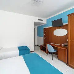 Camera d'albergo con due letti singoli, scrivania e armadio. Ottima per la valutazione hotel.