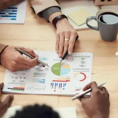 Persone analizzano grafici e dati su un tavolo, discutendo le impostazioni OTA (Over-The-Air) per aggiornamenti software.