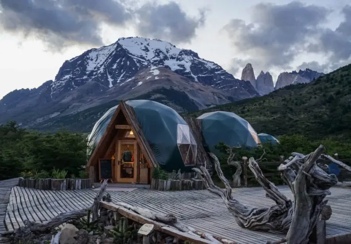 Strutture a cupola verde in un paesaggio montano, che incarnano il **glamping significato**: lusso e natura.