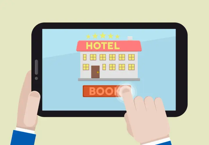 Un dito tocca il pulsante "BOOK" su un tablet che mostra un hotel stilizzato, simbolo dei siti internet hotel per prenotazioni facili.