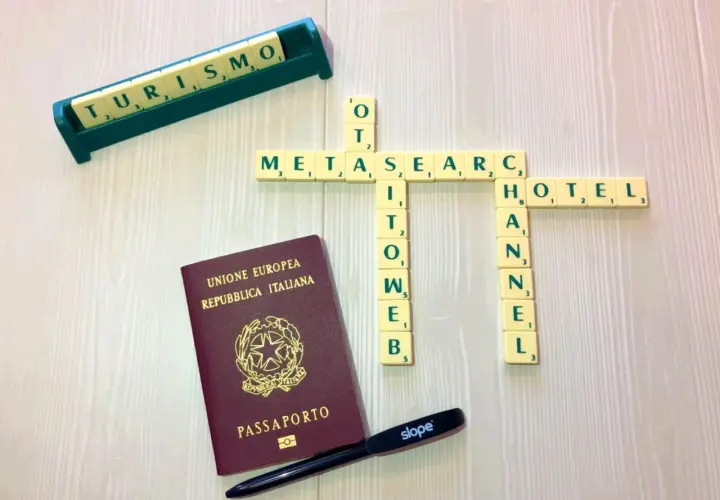 Un passaporto italiano, tessere di parole che formano "METASEARCH", "TURISMO", "HOTEL" e "CHANNEL". Strumenti per pianificare viaggi tramite metamotori di ricerca.