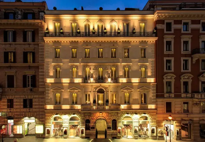 Edificio illuminato di notte, con negozi al piano terra. Si percepisce la differenza tra hotel 3 stelle e 4 stelle dall'eleganza.