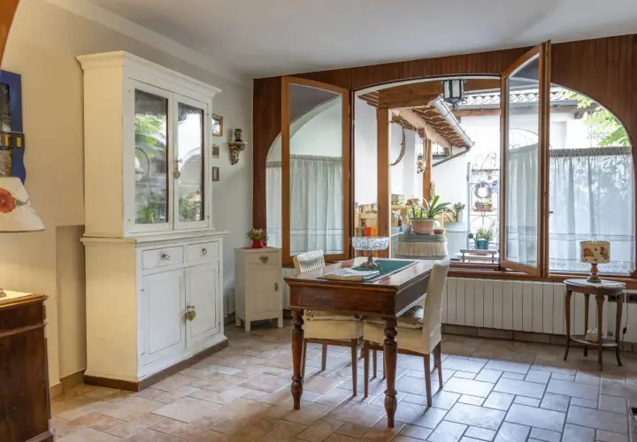 Un tavolo da pranzo con sedie, un mobile bianco e un'ampia finestra che si apre su un cortile. Il **motel significato** qui è un luogo accogliente, non solo un posto dove dormire.