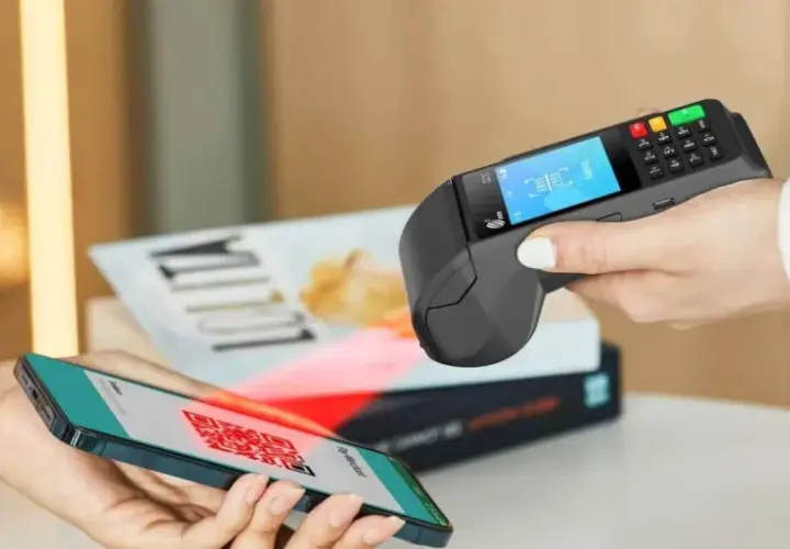 Pagamento contactless con smartphone e sistema pos. Un QR code sullo schermo del telefono viene scansionato dal terminale.