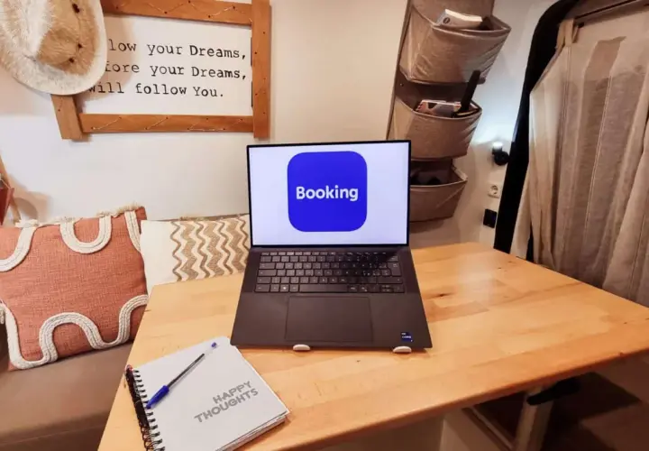 Laptop con app Booking aperta, pronto per un **instant booking** di avventure. Taccuino "Happy Thoughts" accanto.