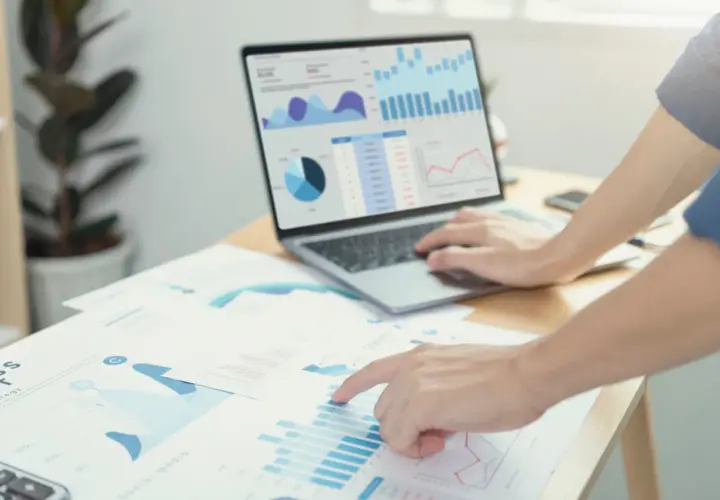 Analisi di grafici e dati di prima parte su un laptop e fogli di carta, con mani che interagiscono con i report.