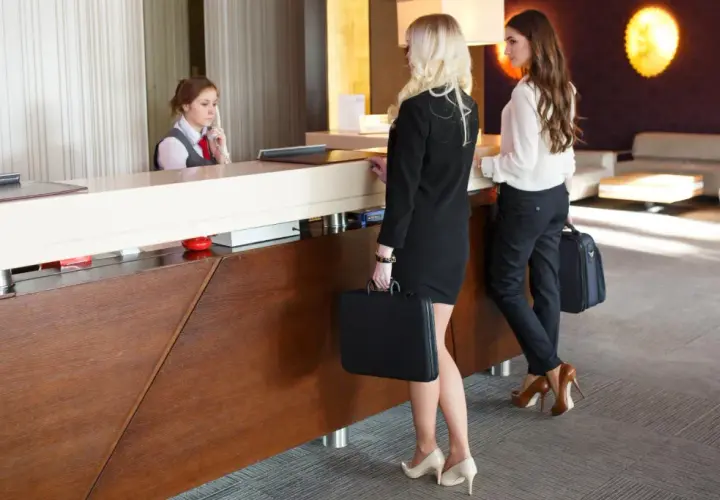 Receptionist in hotel assiste due donne d'affari. Ottimo customer care.