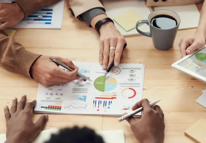 Persone analizzano grafici e dati su un tavolo, discutendo le impostazioni OTA (Over-The-Air) per aggiornamenti software.