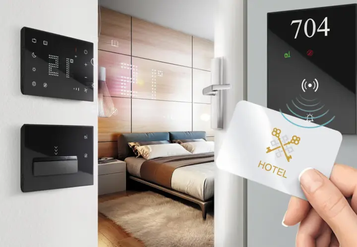 Ingresso in una smart room: una mano avvicina una tessera magnetica a un pannello digitale con il numero 704.