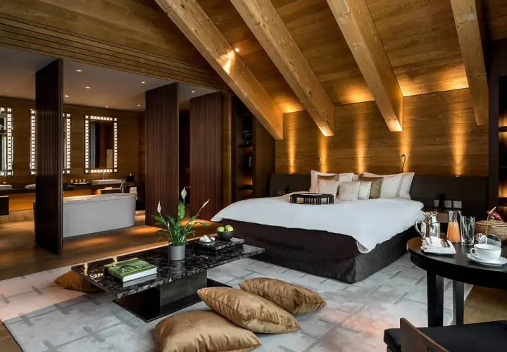 Lussuosa suite con bagno aperto, letto king-size e arredi in legno. Chissà quante stelle può avere un hotel così.