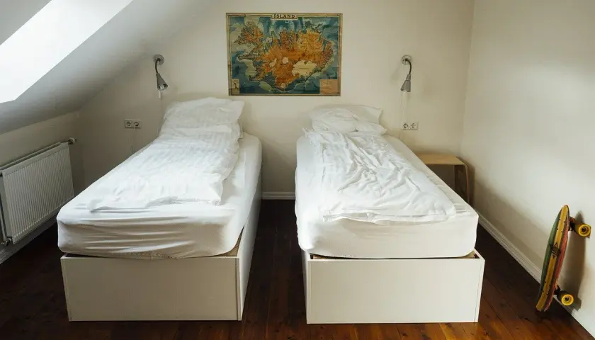 Camera con due letti singoli, mappa dell'Islanda appesa al muro. Un'idea per chi vuole sapere come aprire un ostello.