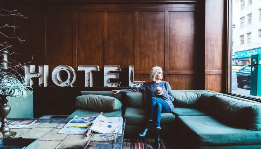 Donna seduta su un divano in un hotel, pensando a un possibile infortunio in albergo e al risarcimento danni.