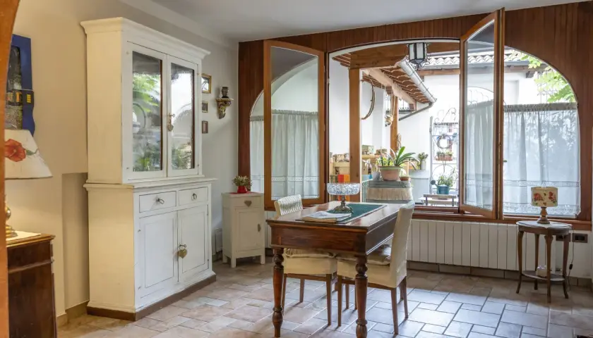 Un tavolo da pranzo con sedie, un mobile bianco e un'ampia finestra che si apre su un cortile. Il **motel significato** qui è un luogo accogliente, non solo un posto dove dormire.