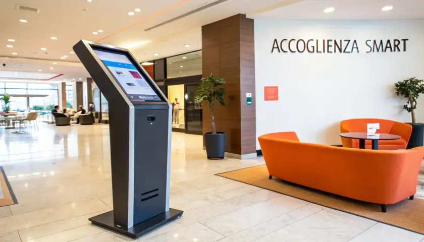 Chiosco per check in automatico b&b. Accoglienza smart con divani arancioni e piante.