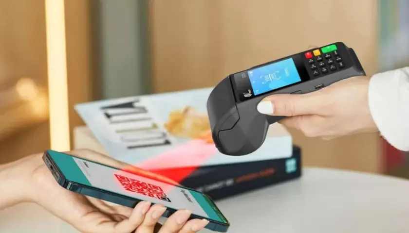 Pagamento contactless con smartphone e sistema pos. Un QR code sullo schermo del telefono viene scansionato dal terminale.