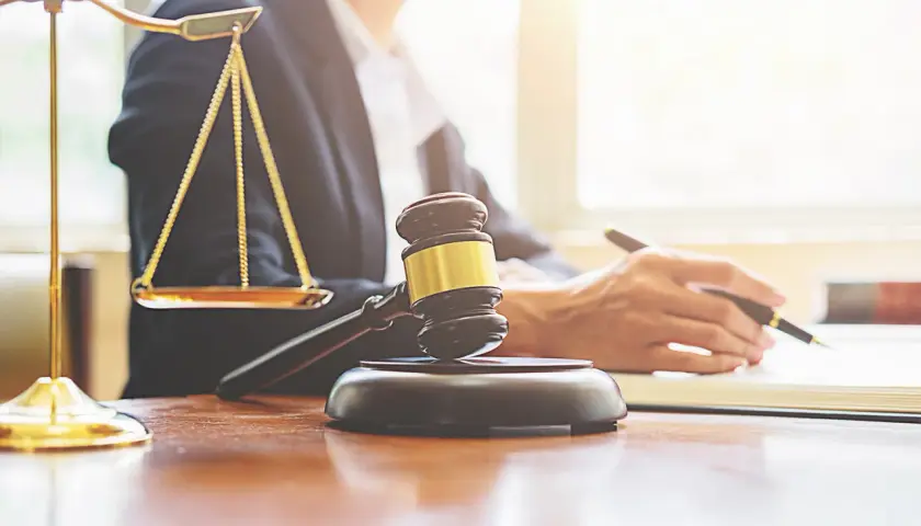 Bilancia della giustizia, martelletto e mano che scrive. Valutare le implicazioni legali per affittare su Airbnb senza partita IVA.