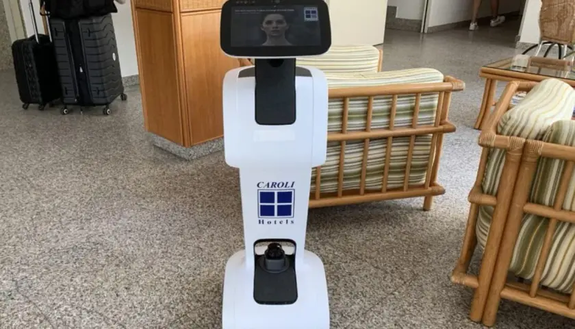 Un hotel robot bianco con logo Caroli Hotels accoglie i visitatori.