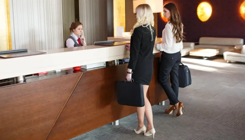 Receptionist in hotel assiste due donne d'affari. Ottimo customer care.