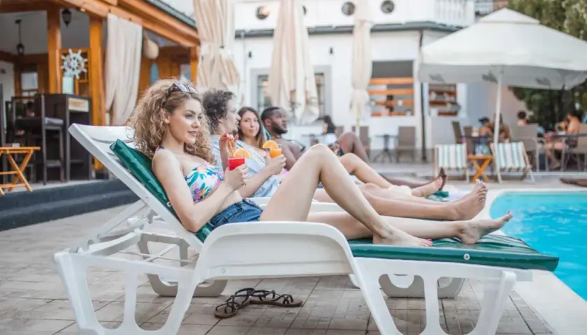 Giovani rilassati a bordo piscina, drink in mano, godendosi il sole. Il vero **soft all inclusive significato** è questo: spensieratezza e comfort totale.