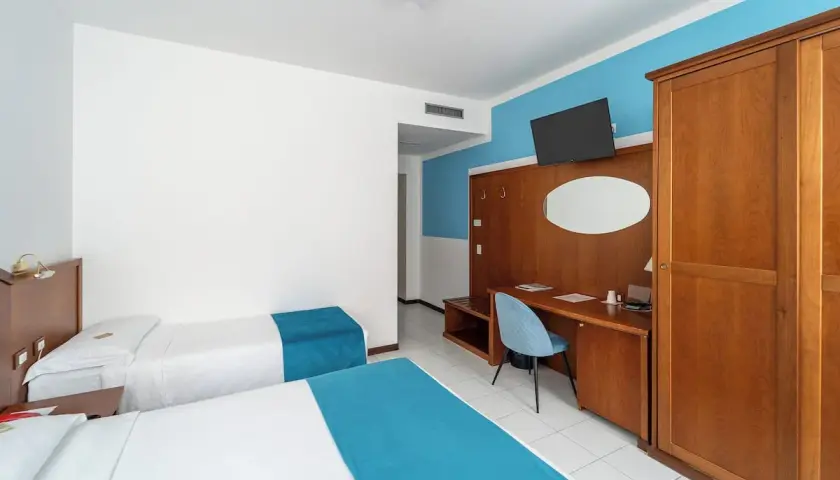 Camera d'albergo con due letti singoli, scrivania e armadio. Ottima per la valutazione hotel.