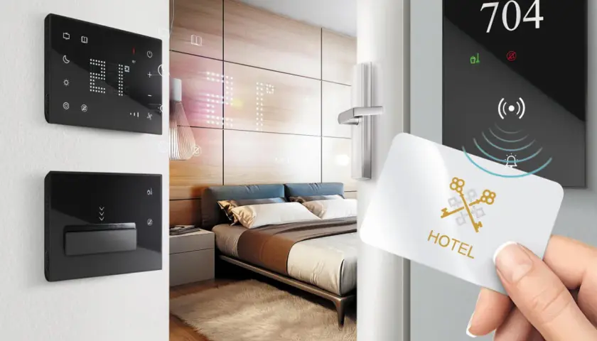 Ingresso in una smart room: una mano avvicina una tessera magnetica a un pannello digitale con il numero 704.
