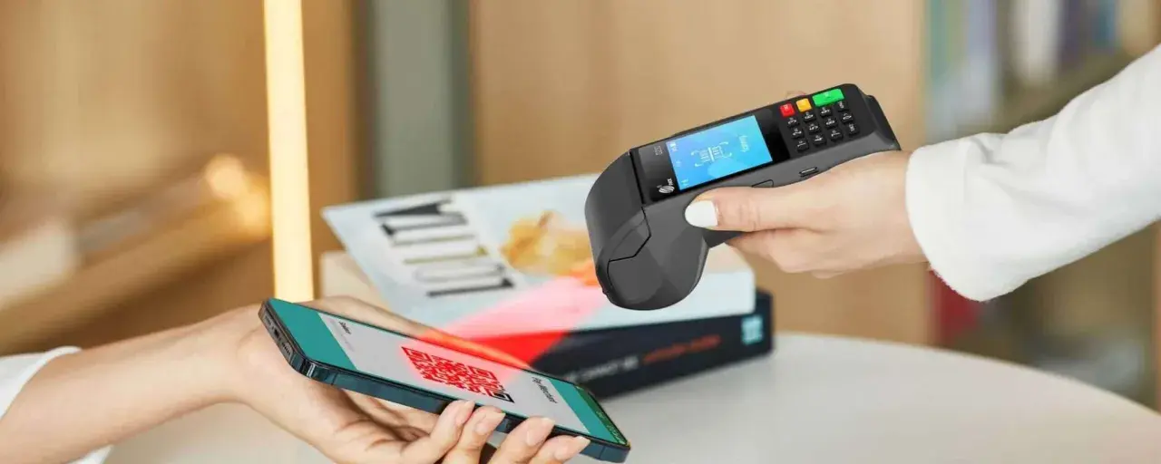 Pagamento contactless con smartphone e sistema pos. Un QR code sullo schermo del telefono viene scansionato dal terminale.