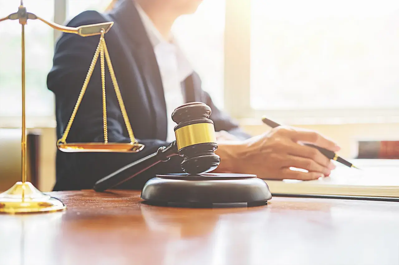 Bilancia della giustizia, martelletto e mano che scrive. Valutare le implicazioni legali per affittare su Airbnb senza partita IVA.