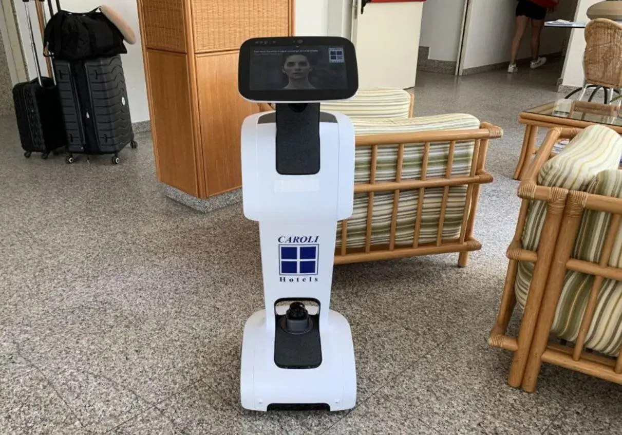 Un hotel robot bianco con logo Caroli Hotels accoglie i visitatori.