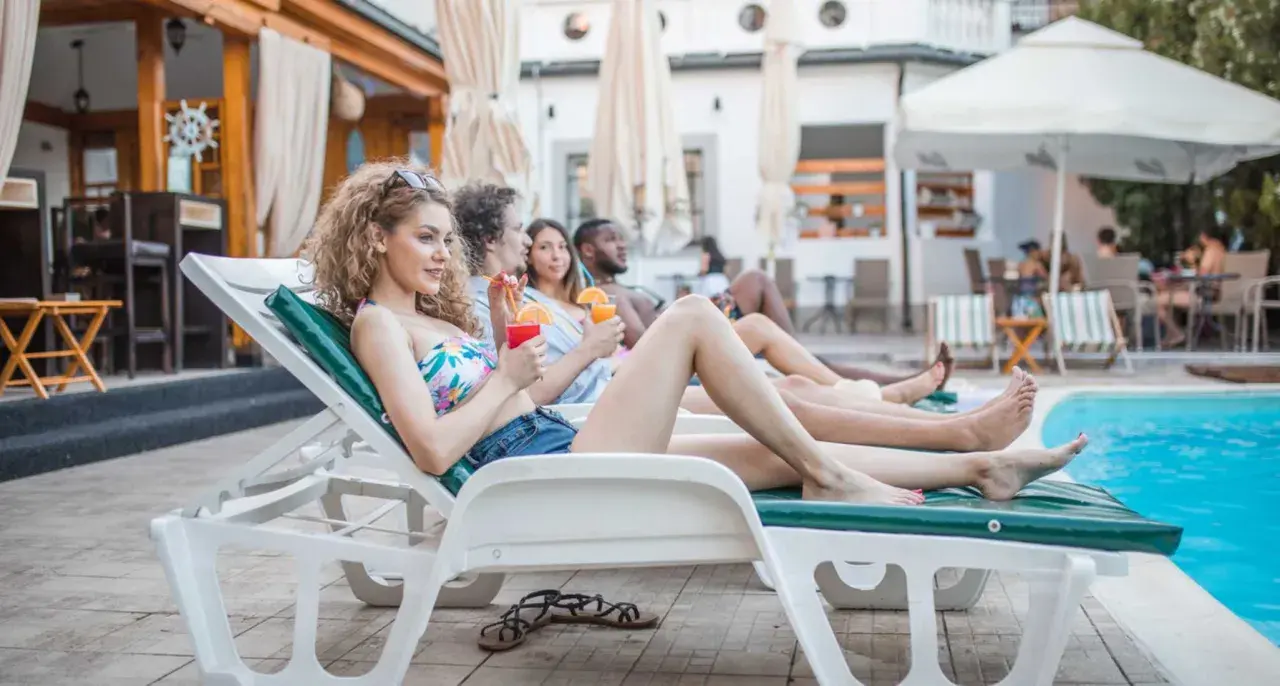 Giovani rilassati a bordo piscina, drink in mano, godendosi il sole. Il vero **soft all inclusive significato** è questo: spensieratezza e comfort totale.