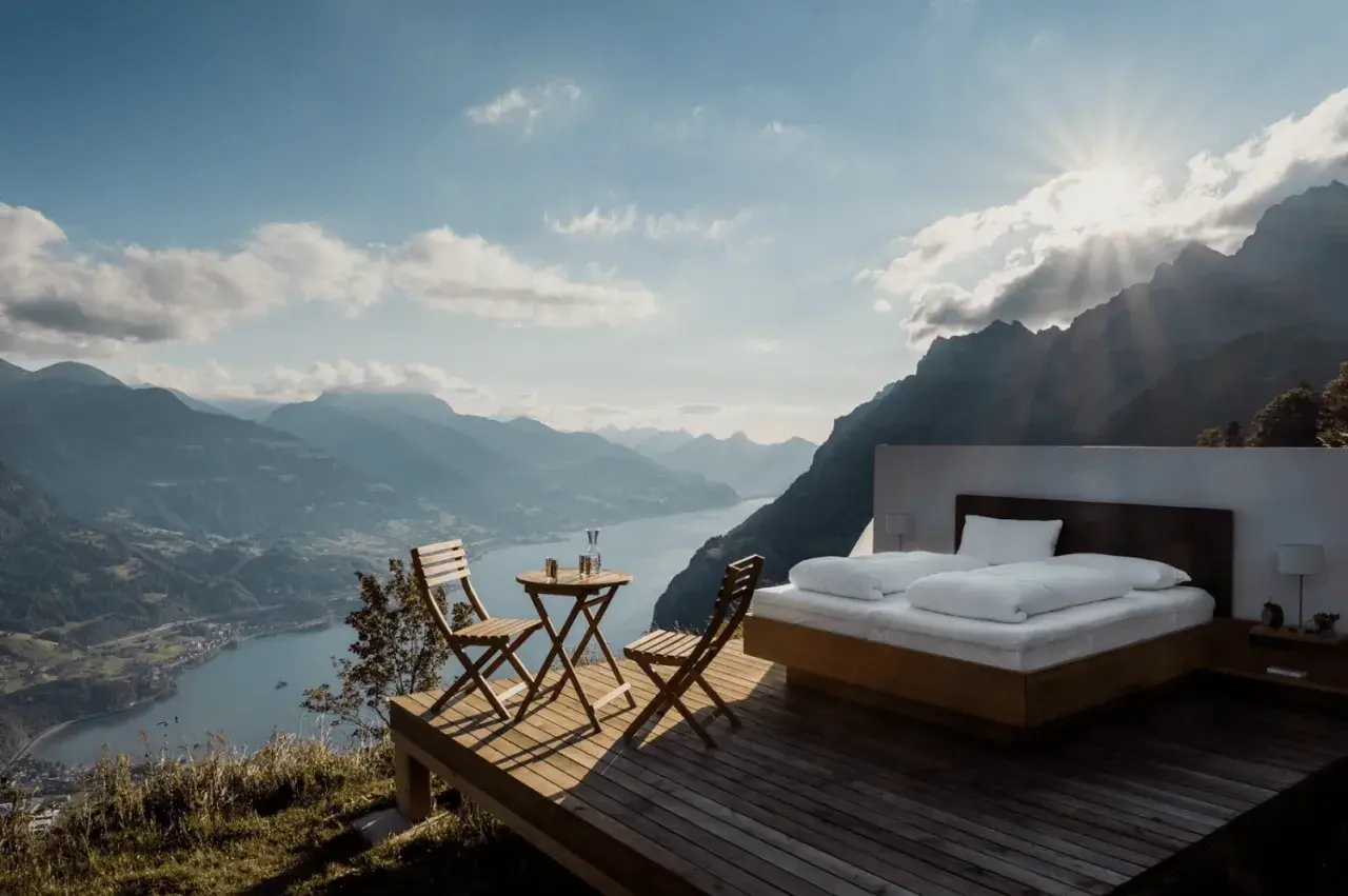 Vista mozzafiato da una casa vacanza: letto king-size, tavolino con sedie e panorama alpino. Pro e contro di un soggiorno così esclusivo.