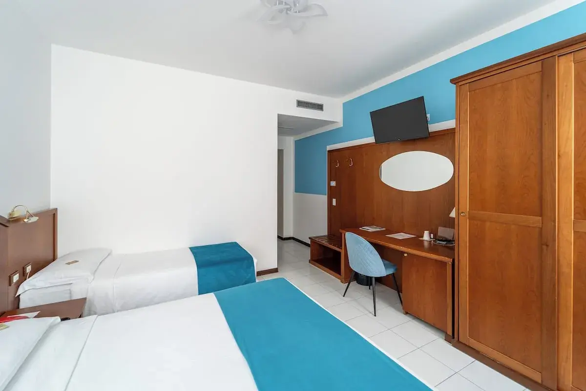 Camera d'albergo con due letti singoli, scrivania e armadio. Ottima per la valutazione hotel.