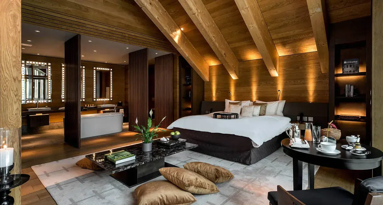 Lussuosa suite con bagno aperto, letto king-size e arredi in legno. Chissà quante stelle può avere un hotel così.