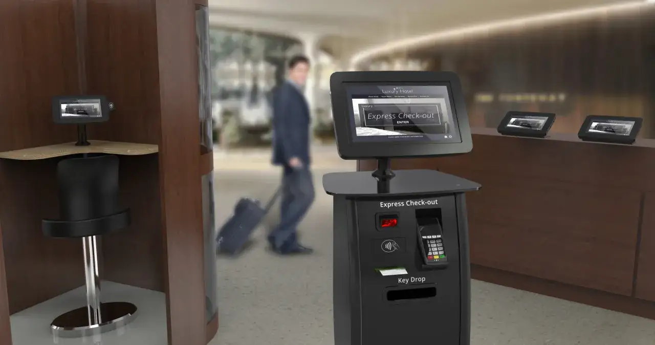 Un uomo con valigia passa davanti a un chiosco per il software check-in dell'hotel.