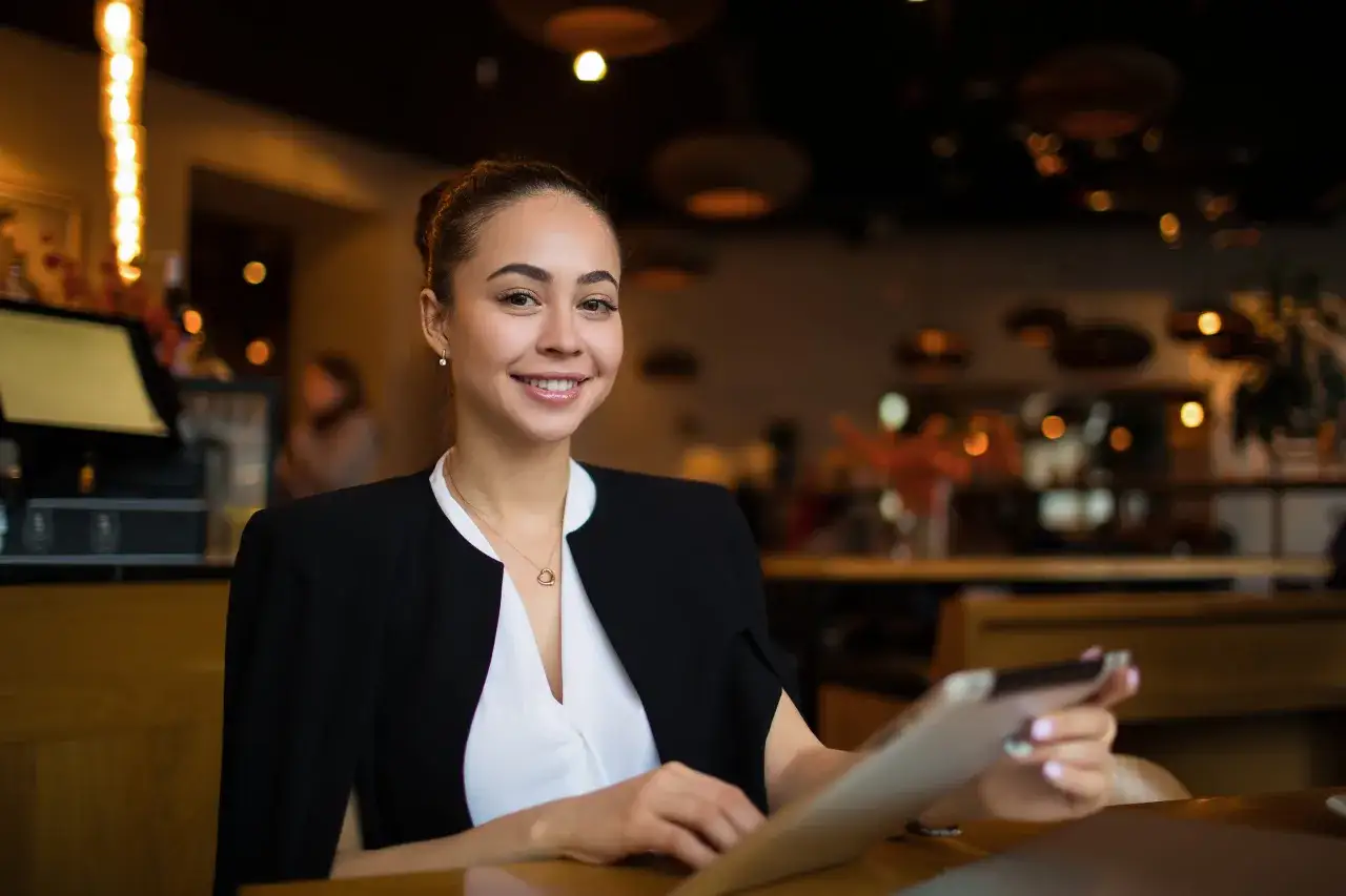 Sorriso di una back office manager che lavora al tablet in un ambiente accogliente.