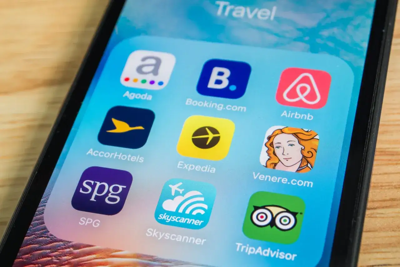 Schermata di un telefono con app di viaggio: Agoda, Booking.com, Airbnb, AccorHotels, Expedia, Venere.com, SPG, Skyscanner, TripAdvisor. Cosa significa prezzo solo su mobile?