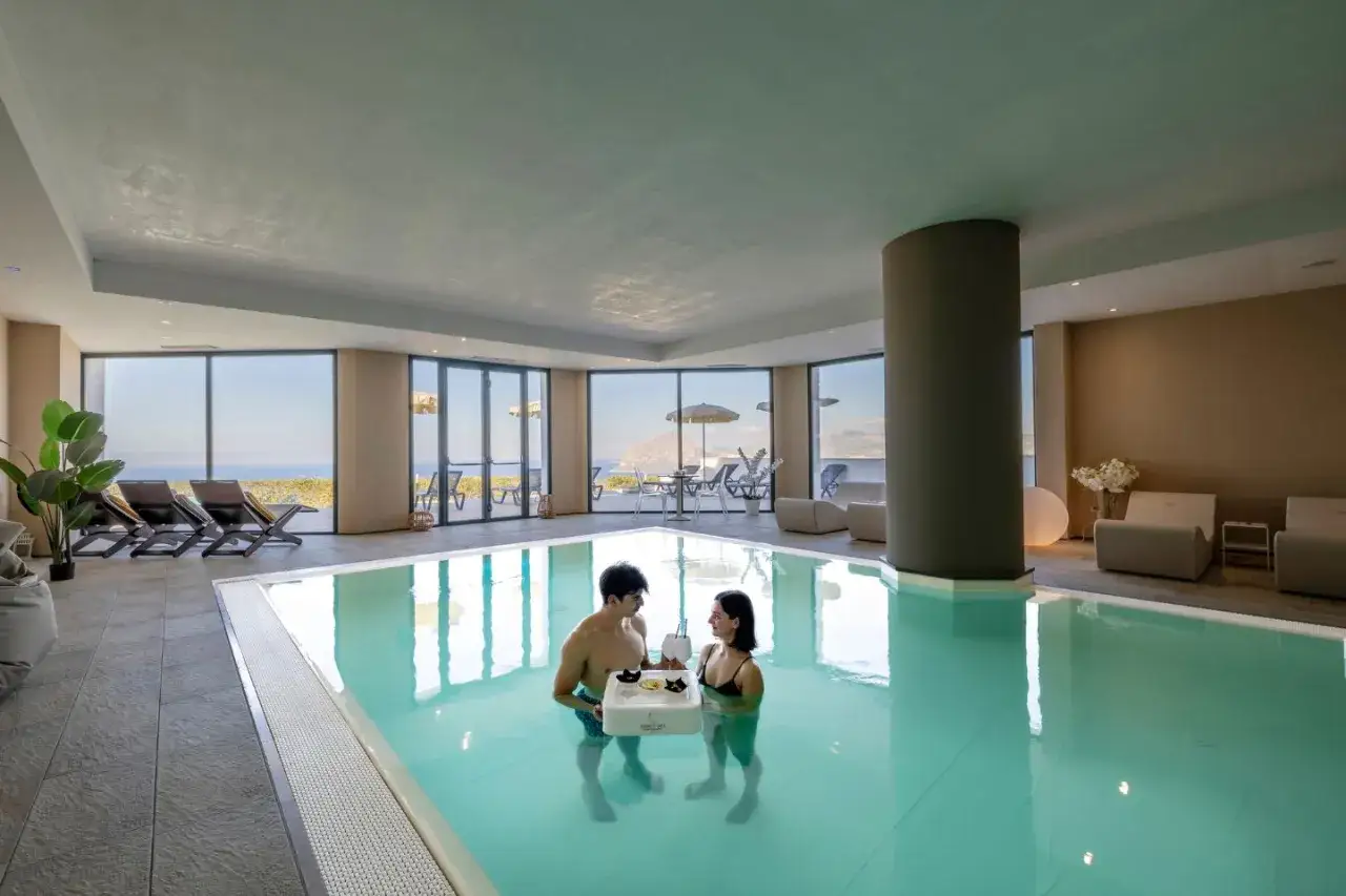Coppia in piscina con vassoio galleggiante, un esempio delle caratteristiche hotel 4 stelle con vista mare e aree relax.