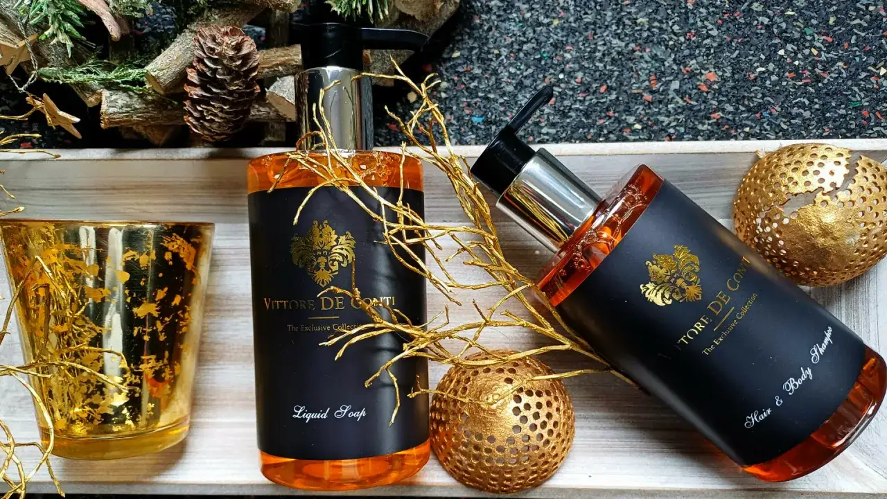 Saponi liquidi e shampoo, parte degli amenities hotel cosa sono, con decorazioni dorate e pigne.