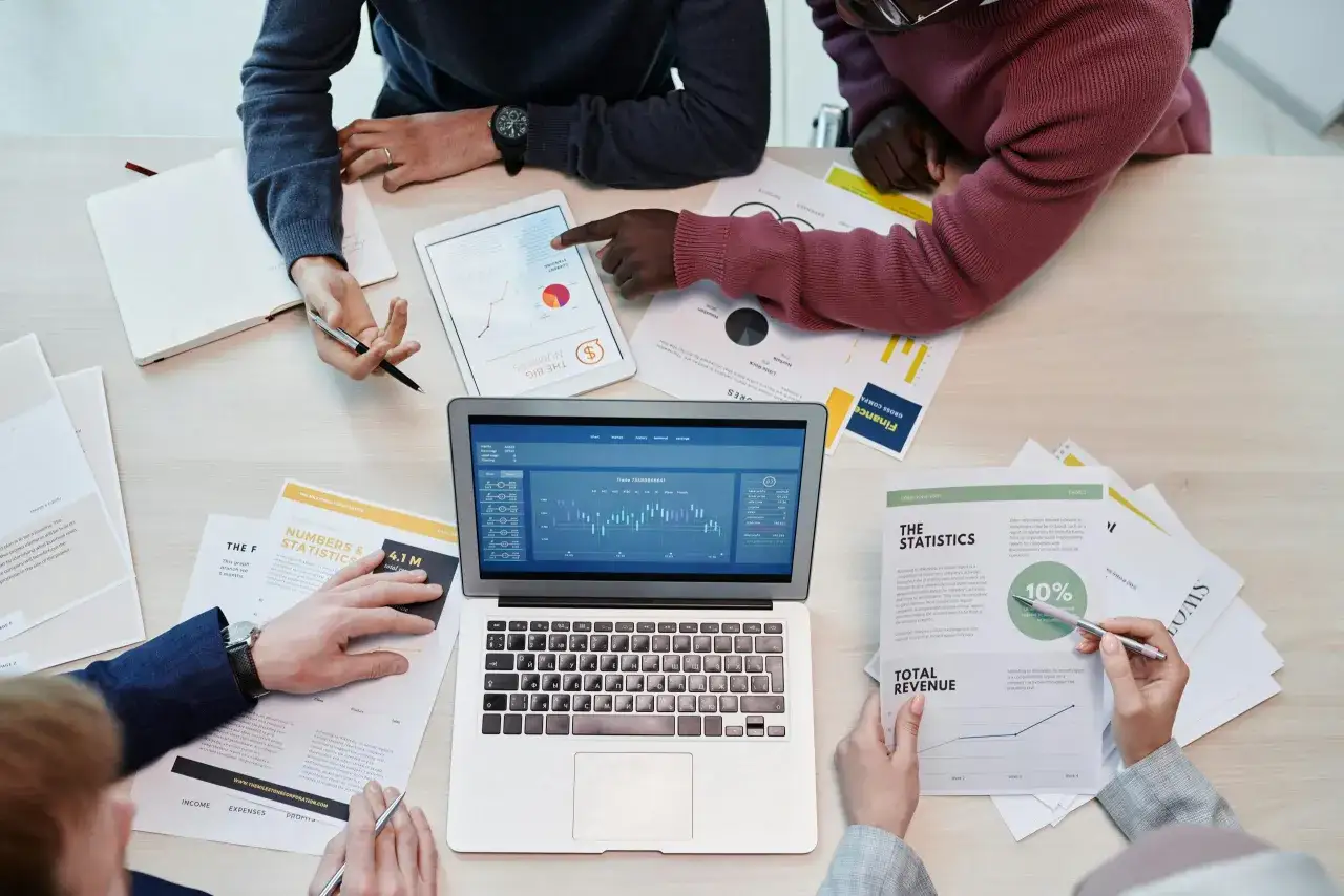 Analisi dati finanziari per la web reputation aziendale. Team discute grafici e report su tablet e laptop.