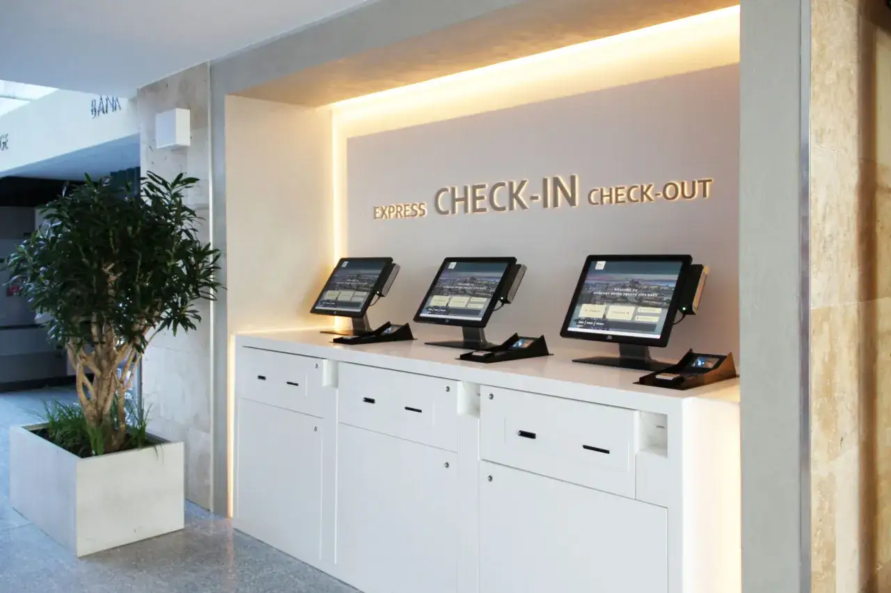 Postazioni per il check-in online e check-out in hotel, con schermi touch e un'elegante illuminazione.