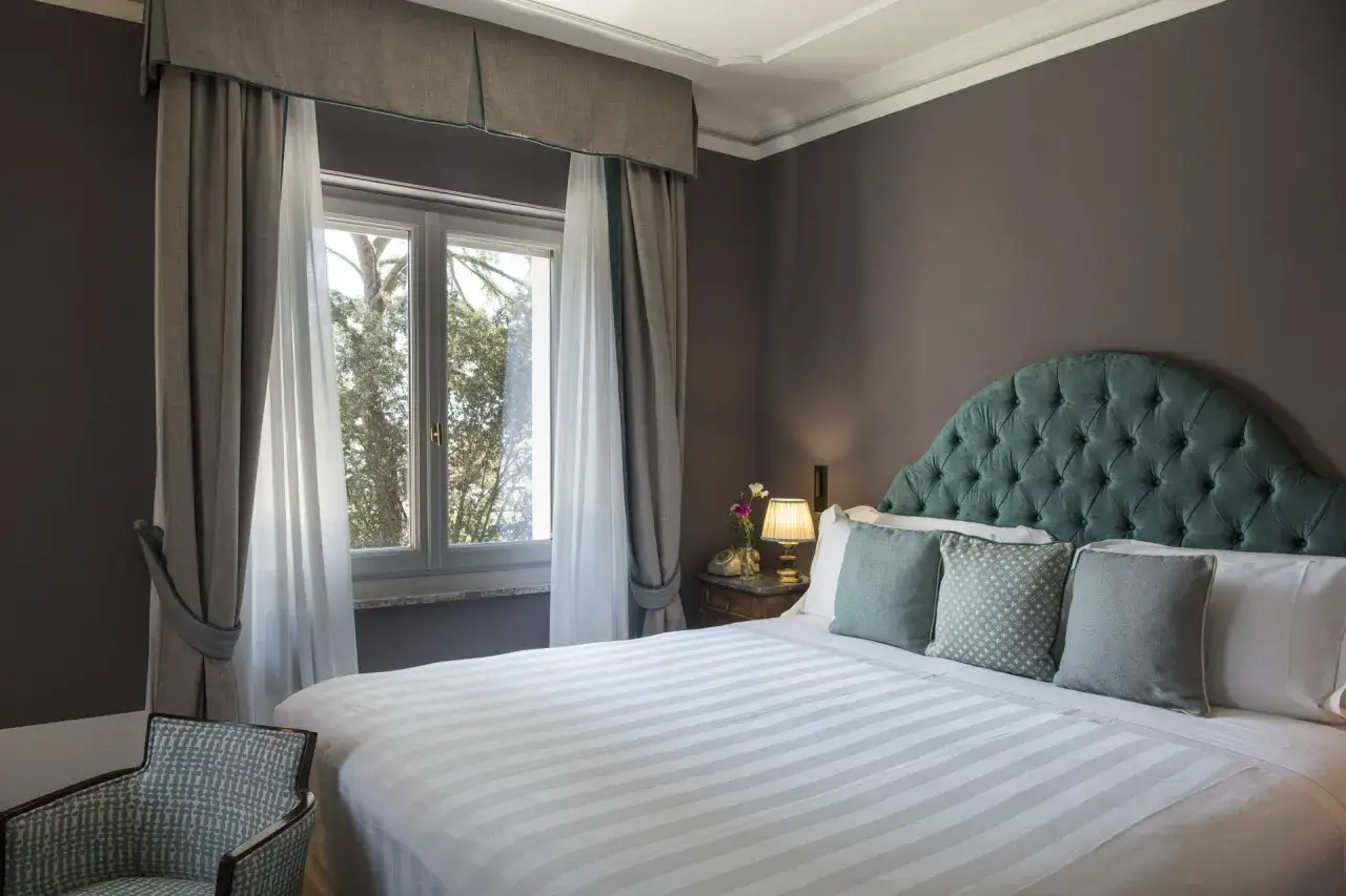 Camera elegante con letto king size, testiera capitonné verde acqua e vista sul giardino. Ottime idee nomi camere per un soggiorno da sogno.