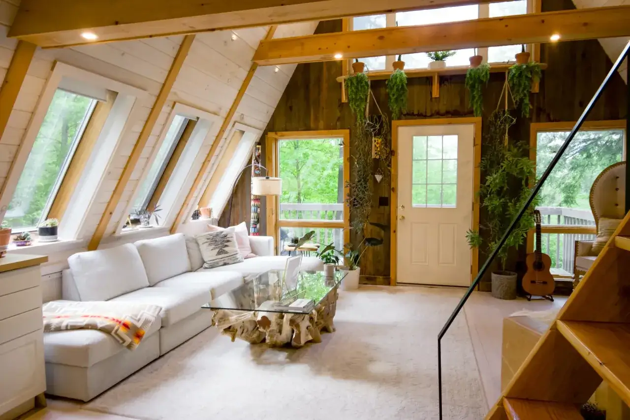 Accogliente soggiorno con divano bianco, tavolino in legno grezzo e tante piante. Un'ottima opzione per un alternative Airbnb immerso nella natura.